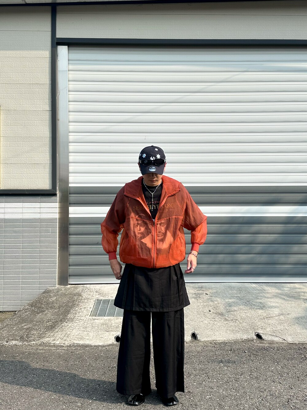 オレンジ系のジャケット/アウター、ブラック系のパンツ、ブルー系のキャップを着用したメンズの春コーディネートの2枚目の写真