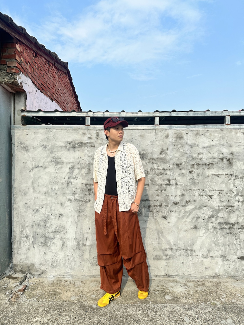 オレンジ系のパンツ、ホワイト系のトップス、ブラック系のタンクトップを着用したメンズの春コーディネートの3枚目の写真