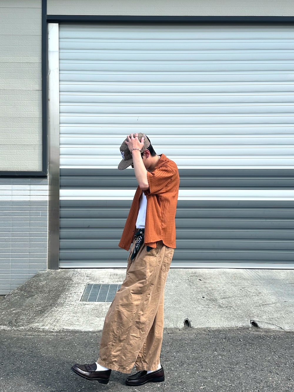 オレンジ系のシャツ/ブラウス、ブラウン系のローファー、ホワイト系のタンクトップを着用したメンズの春コーディネートの2枚目の写真