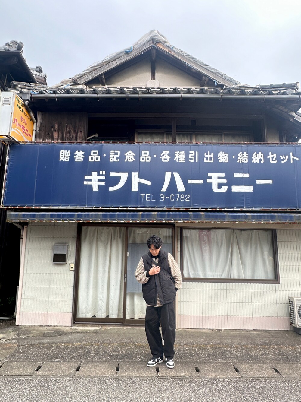 イエロー系のポロシャツ、ブラック系のベスト、ブラック系のスニーカーを着用したメンズの冬コーディネートの3枚目の写真