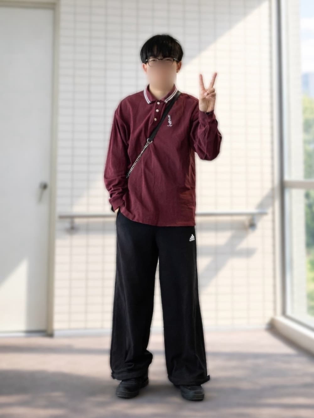 ブラック系のショルダーバッグ、ブラック系のスウェットパンツ、レッド系のポロシャツを着用したメンズの春コーディネートの2枚目の写真