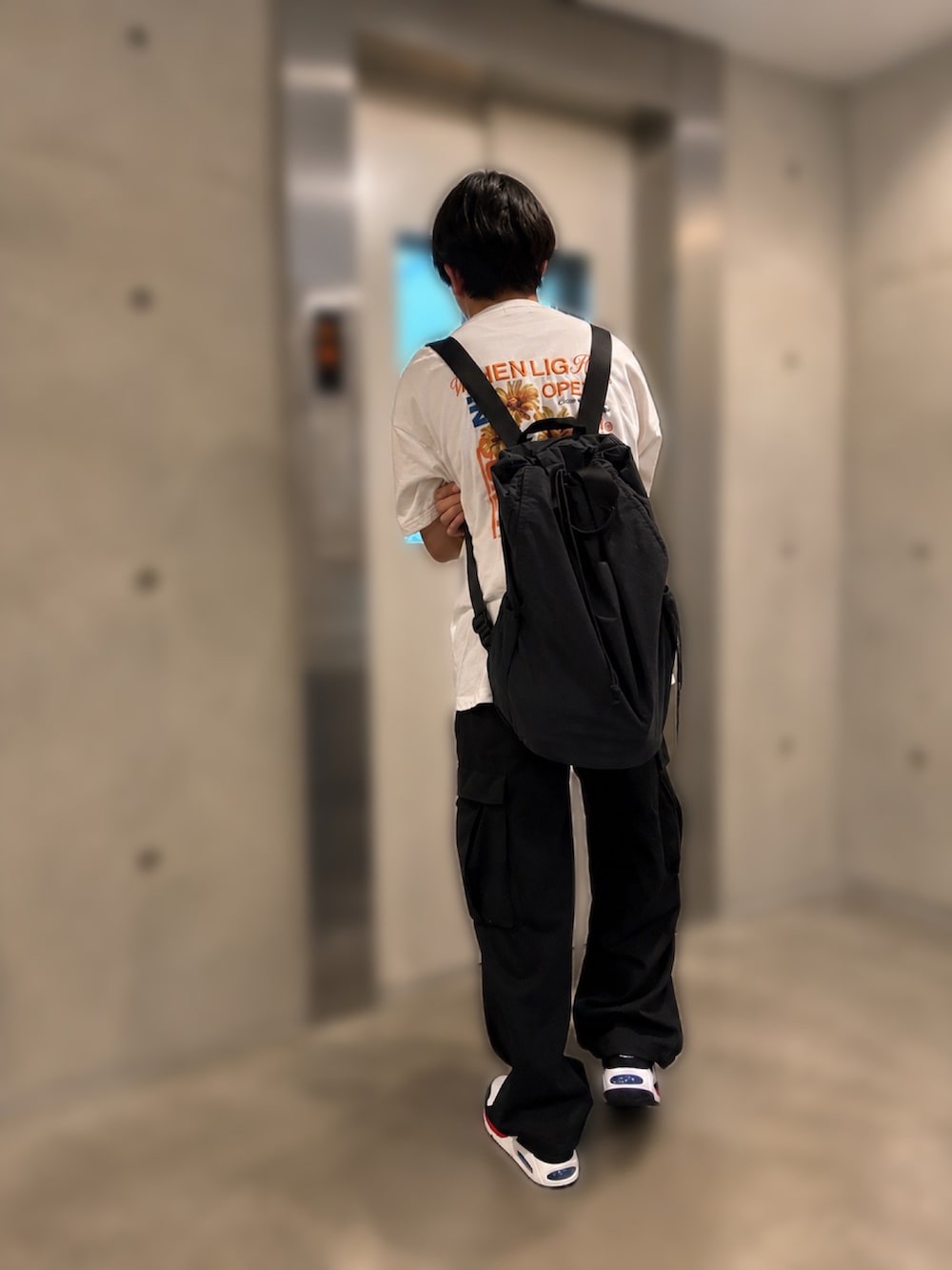 ブラック系のカーゴパンツ、ホワイト系のスニーカー、ホワイト系のTシャツ/カットソーを着用したメンズの夏コーディネートの2枚目の写真
