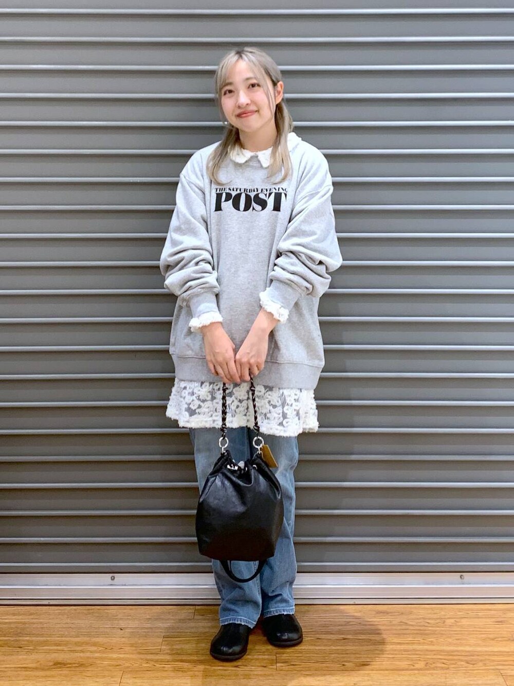 ブラック系のショルダーバッグ、ブルー系のデニムパンツ、ブラック系のブーツを着用したレディースの冬コーディネートの5枚目の写真