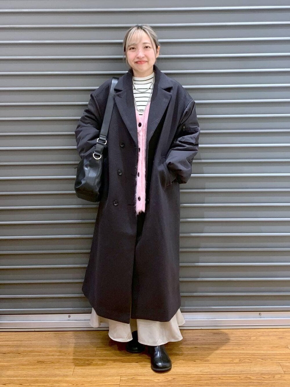 ブラック系のショルダーバッグ、ホワイト系のニット/セーター、ブラック系のブーツを着用したレディースの冬コーディネートの8枚目の写真