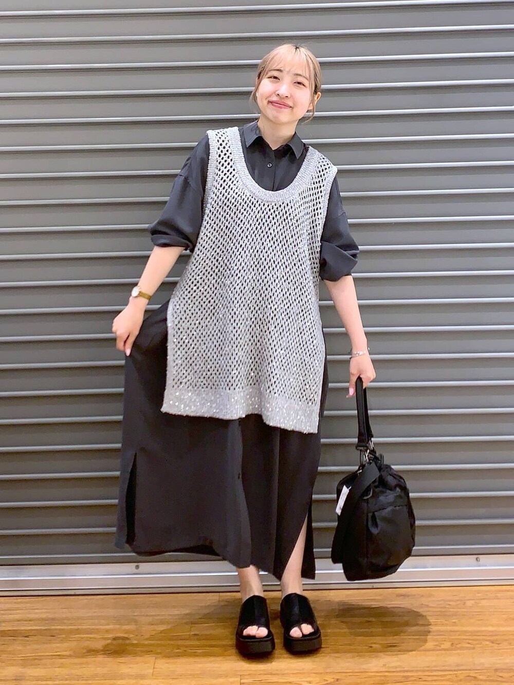 グレー系のベスト、グレー系のワンピース、ブラック系のショルダーバッグを着用したレディースの春コーディネートの6枚目の写真