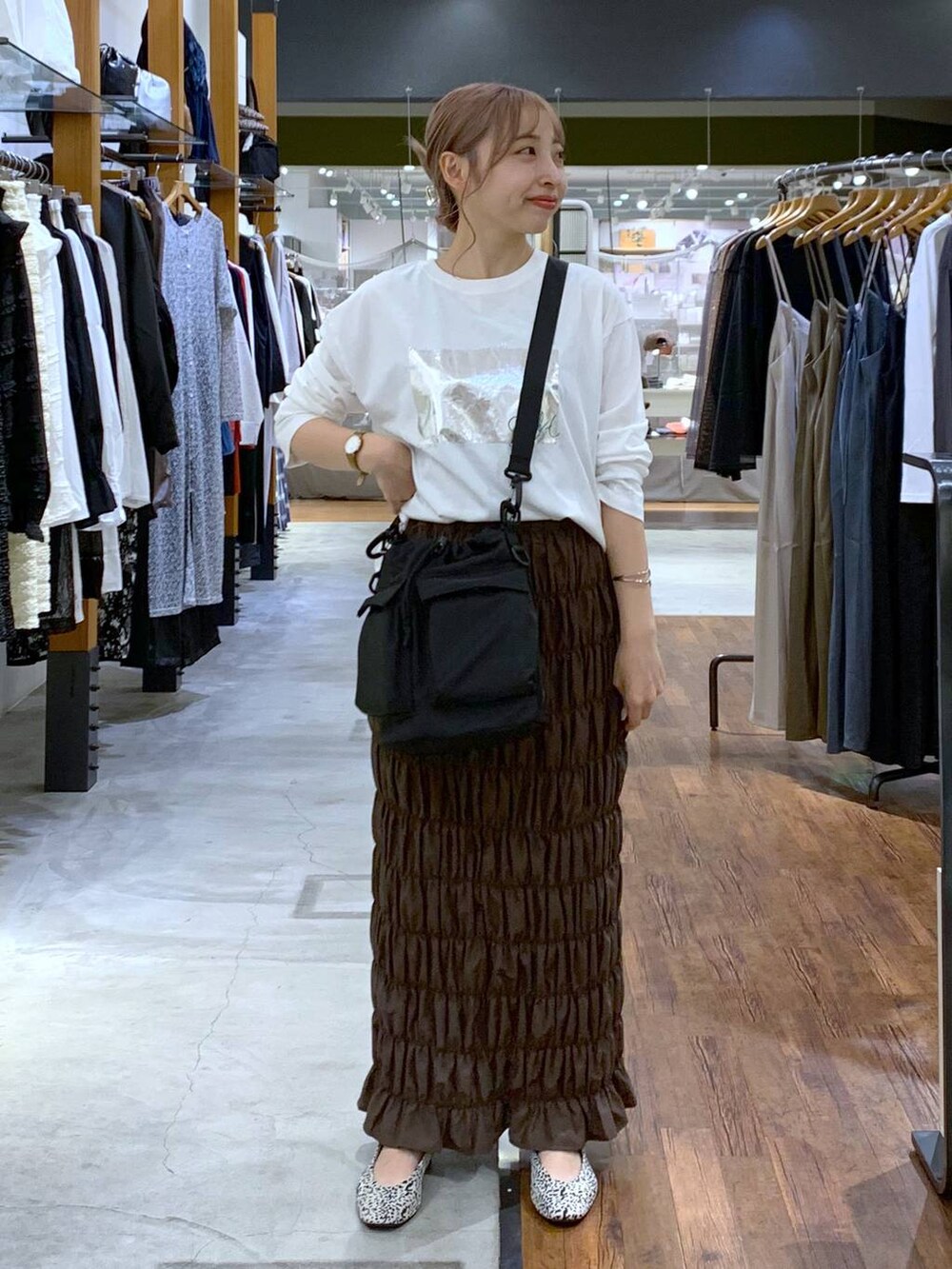 ブラック系のショルダーバッグ、ホワイト系のパンプス、イエロー系のスカートを着用したレディースの秋コーディネートの7枚目の写真