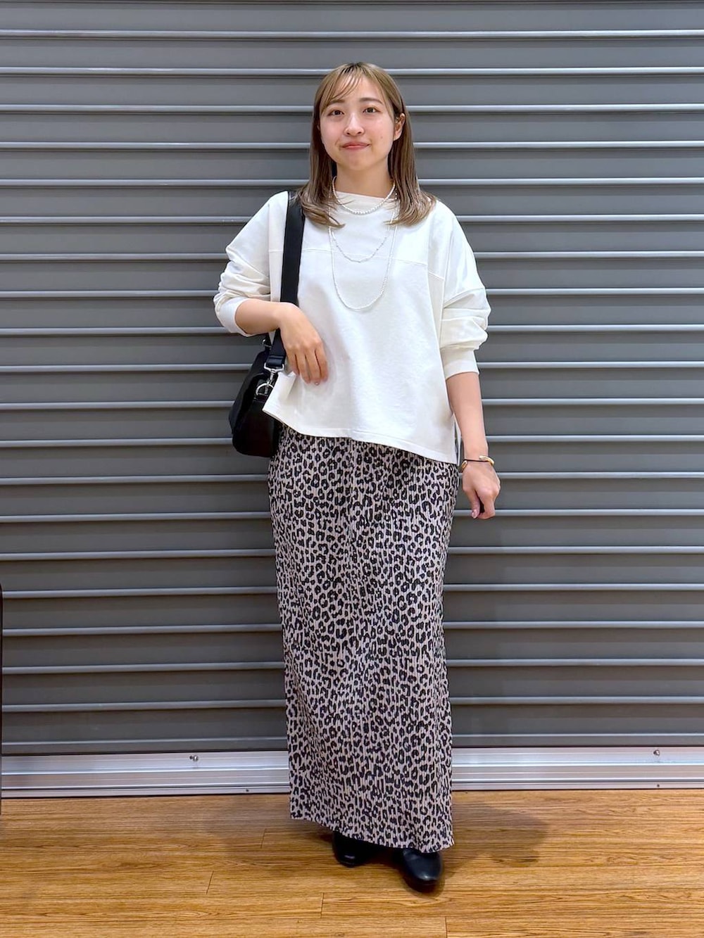 ブラック系のショルダーバッグ、ホワイト系のTシャツ/カットソー、ブラック系のパンプスを着用したレディースの春コーディネートの6枚目の写真