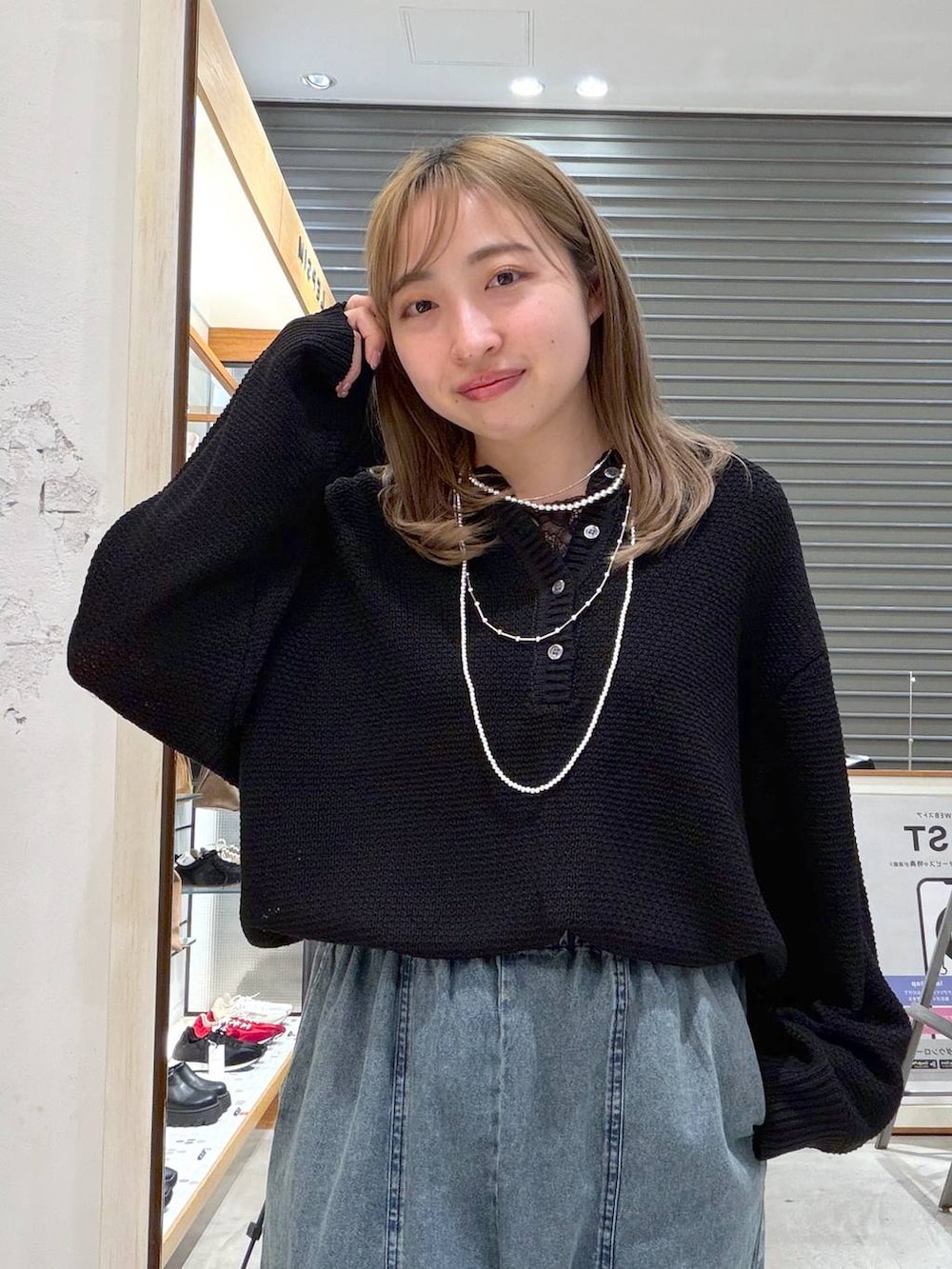 ブラック系のニット/セーター、ブルー系のデニムパンツ、シルバー系のネックレスを着用したレディースの春コーディネートの6枚目の写真