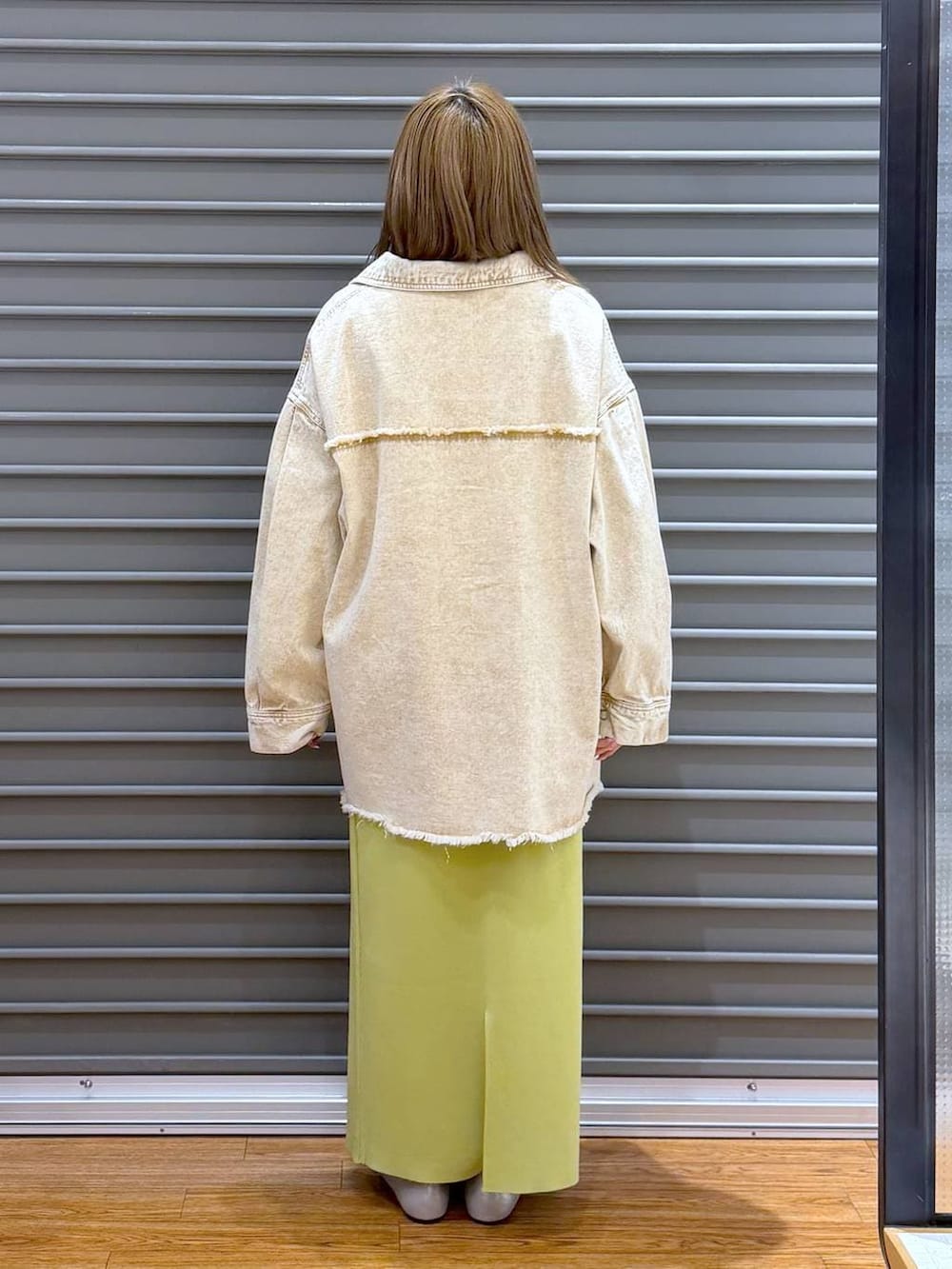 グリーン系のスカート、シルバー系のパンプス、ホワイト系のトートバッグを着用したレディースの春コーディネートの2枚目の写真