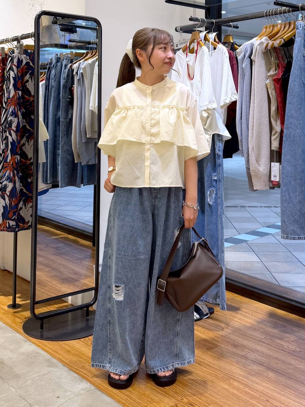 ブルー系のデニムパンツ、ホワイト系のサンダル、ブラウン系のショルダーバッグを着用したレディースの夏コーディネートの5枚目の写真