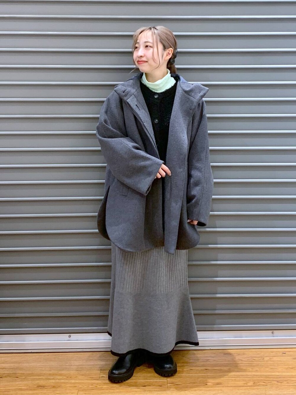 ホワイト系のショルダーバッグ、グレー系のポンチョ、ブラック系のブーツを着用したレディースの冬コーディネートの4枚目の写真