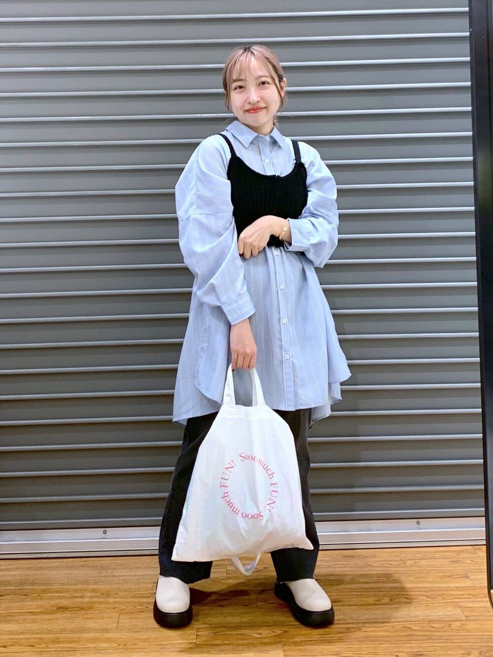 ブラック系のニット/セーター、ブルー系のチュニック、ホワイト系のトートバッグを着用したレディースの春コーディネートの5枚目の写真