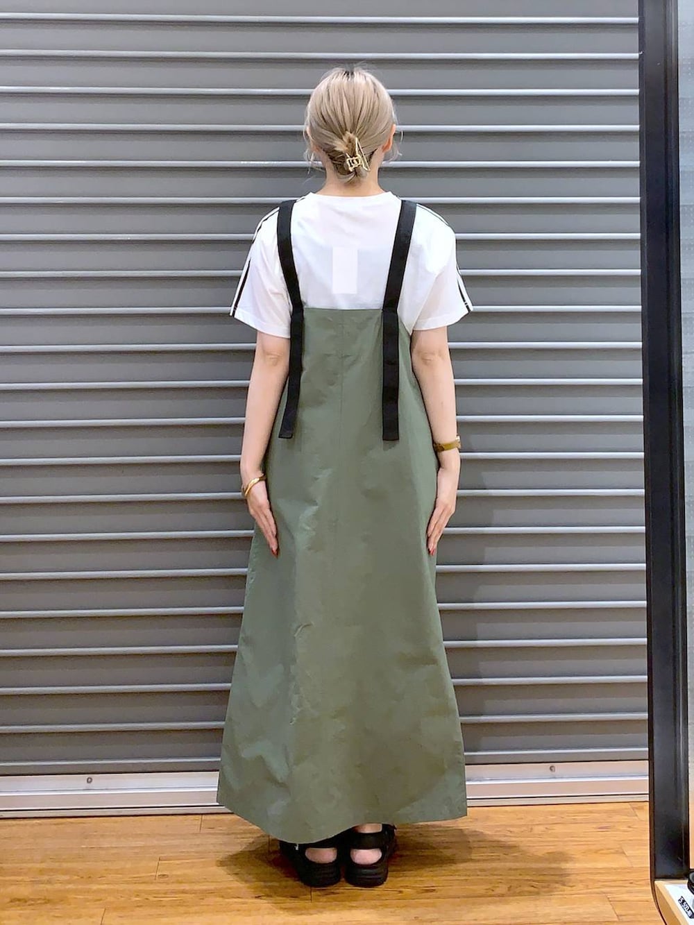 グリーン系のジャンパースカート、ブラック系のサンダル、ブラック系のショルダーバッグを着用したレディースの夏コーディネートの2枚目の写真