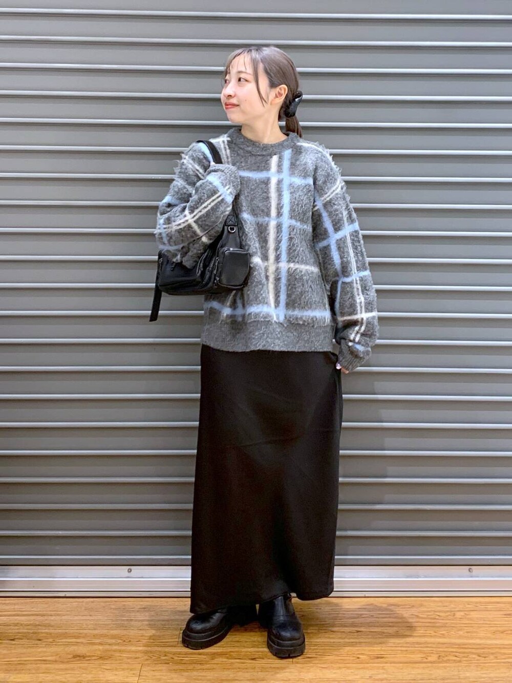 ブラック系のスカート、ブラック系のブーツ、ブラック系のショルダーバッグを着用したレディースの冬コーディネートの5枚目の写真