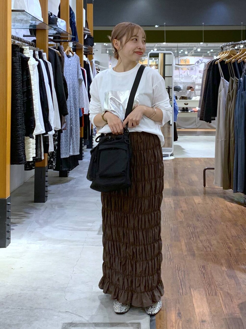 ブラック系のショルダーバッグ、ホワイト系のパンプス、イエロー系のスカートを着用したレディースの秋コーディネートの4枚目の写真