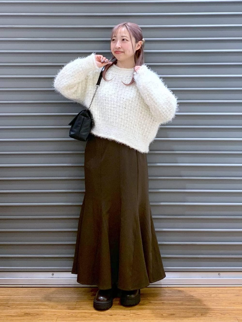 ブラウン系のブーツ、ホワイト系のニット/セーター、ブラック系のショルダーバッグを着用したレディースの冬コーディネートの6枚目の写真