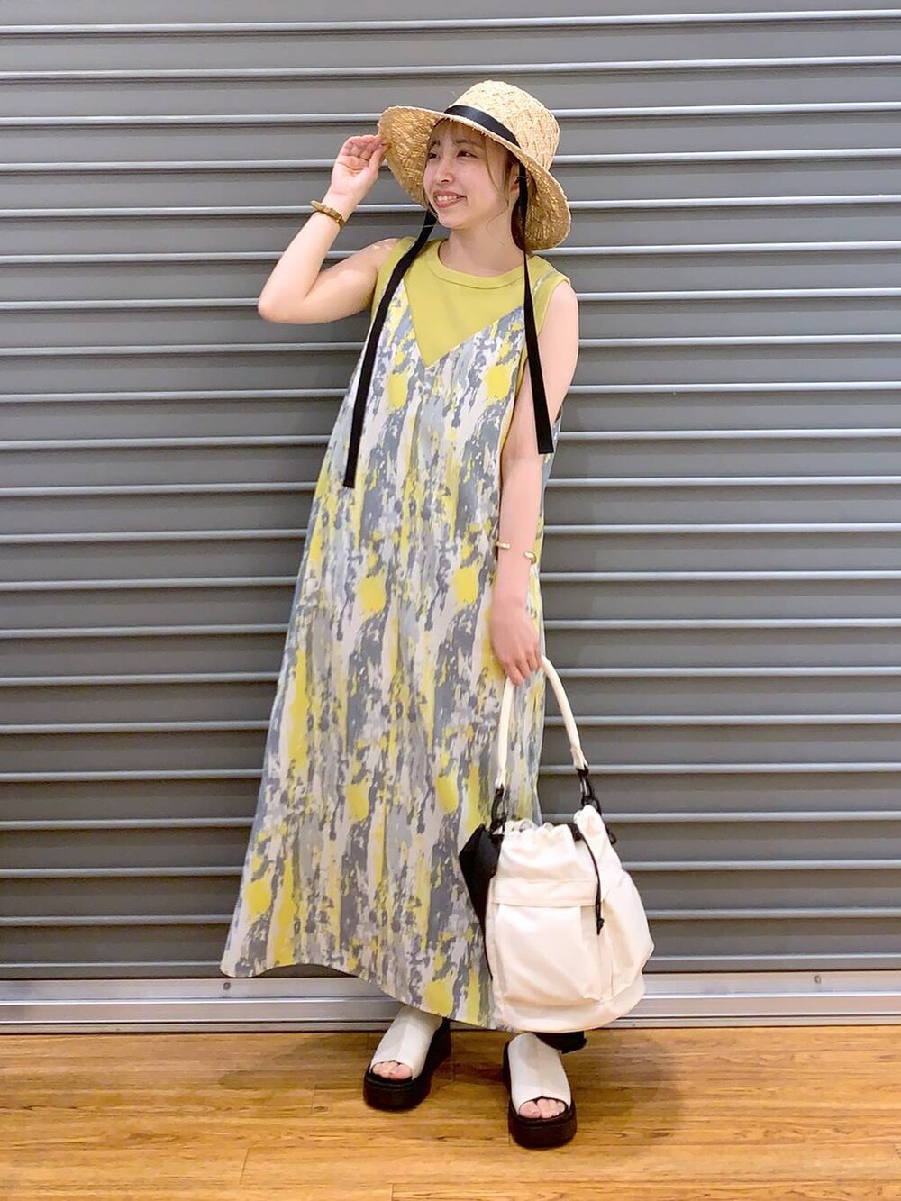 イエロー系のワンピース、イエロー系のタンクトップ、ホワイト系のショルダーバッグを着用したレディースの春コーディネートの6枚目の写真