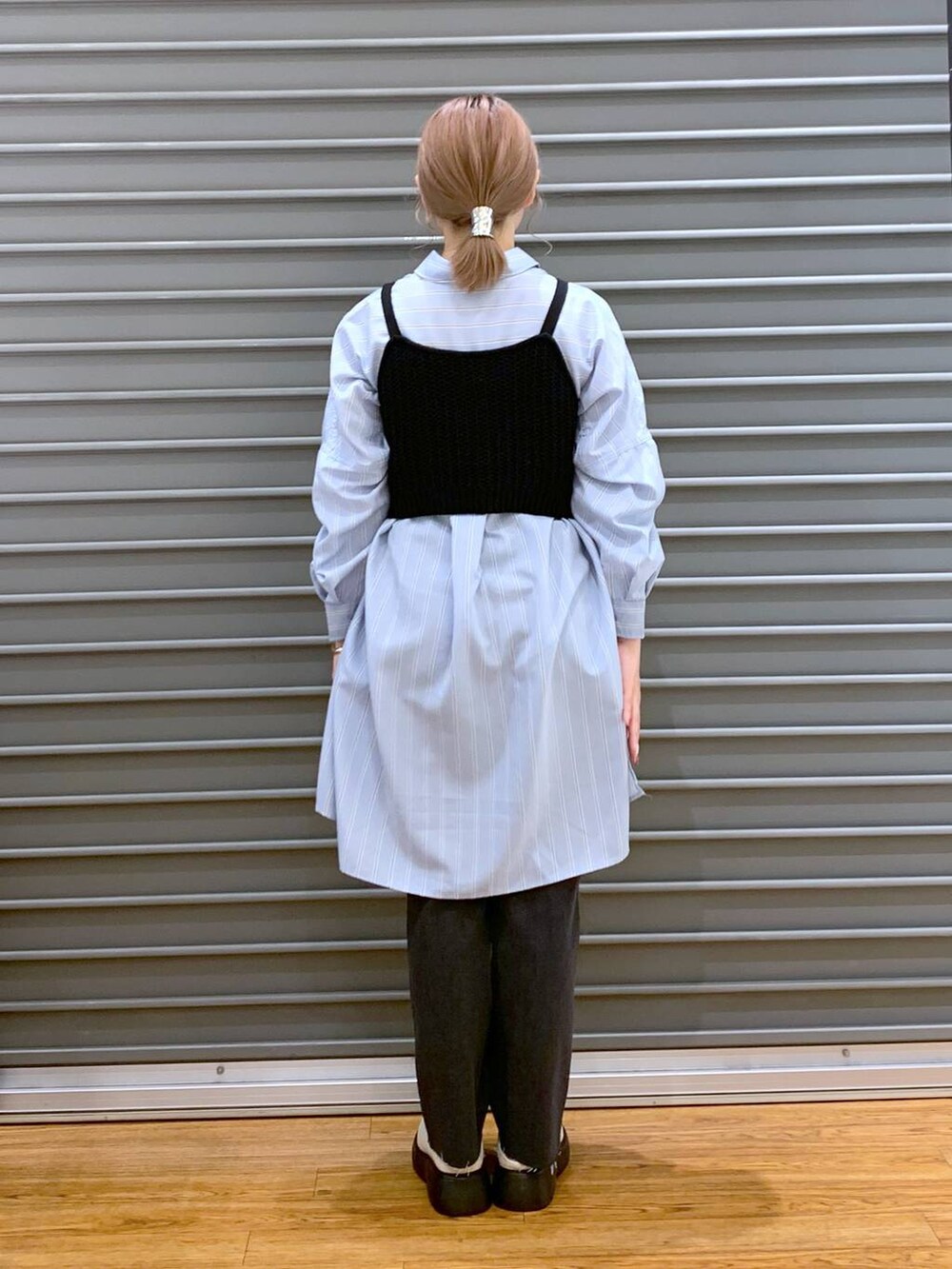 ブラック系のニット/セーター、ブルー系のチュニック、ホワイト系のトートバッグを着用したレディースの春コーディネートの2枚目の写真