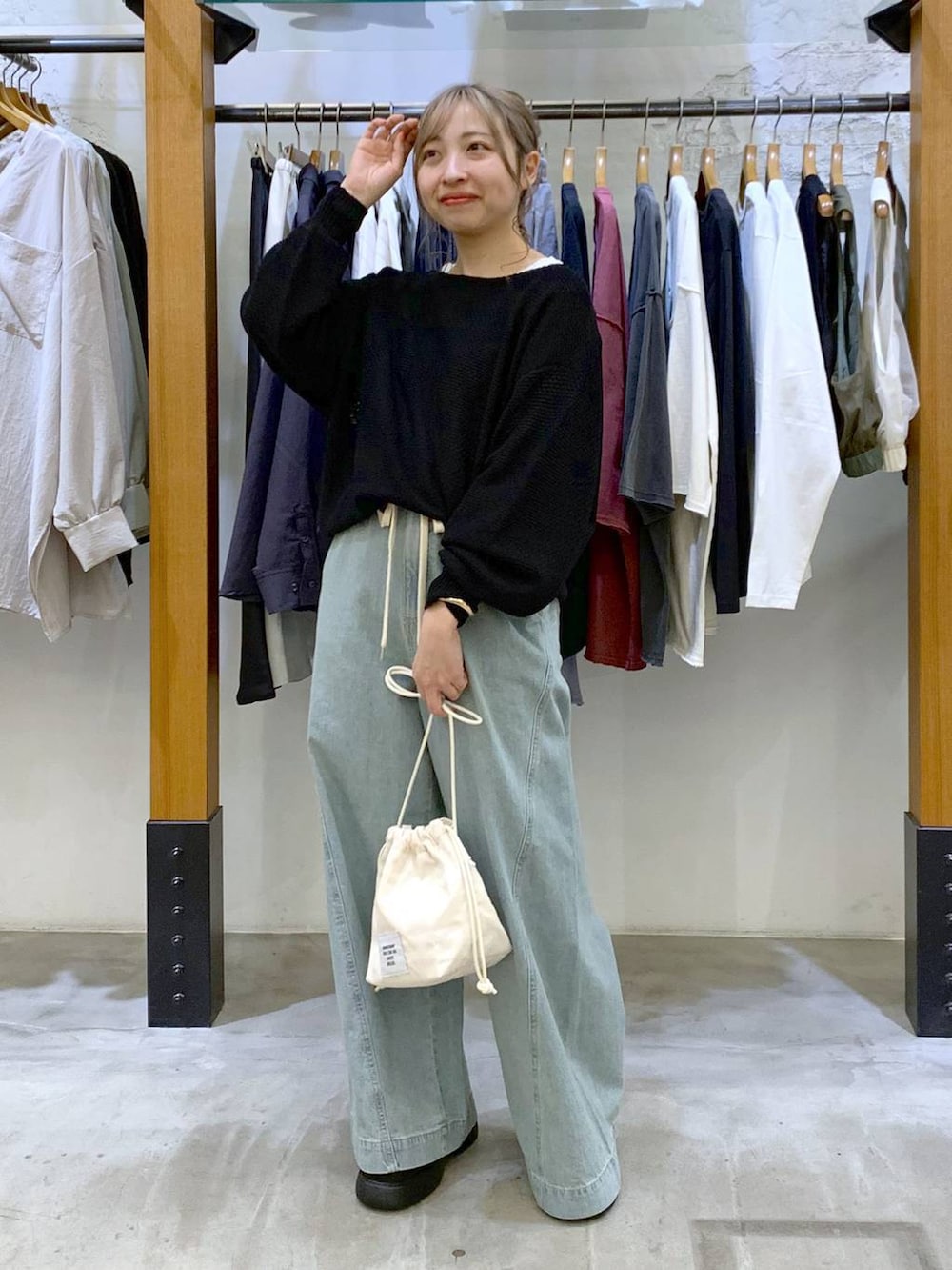 ブラック系のニット/セーター、ホワイト系のショルダーバッグ、ブルー系のデニムパンツを着用したレディースの春コーディネートの4枚目の写真