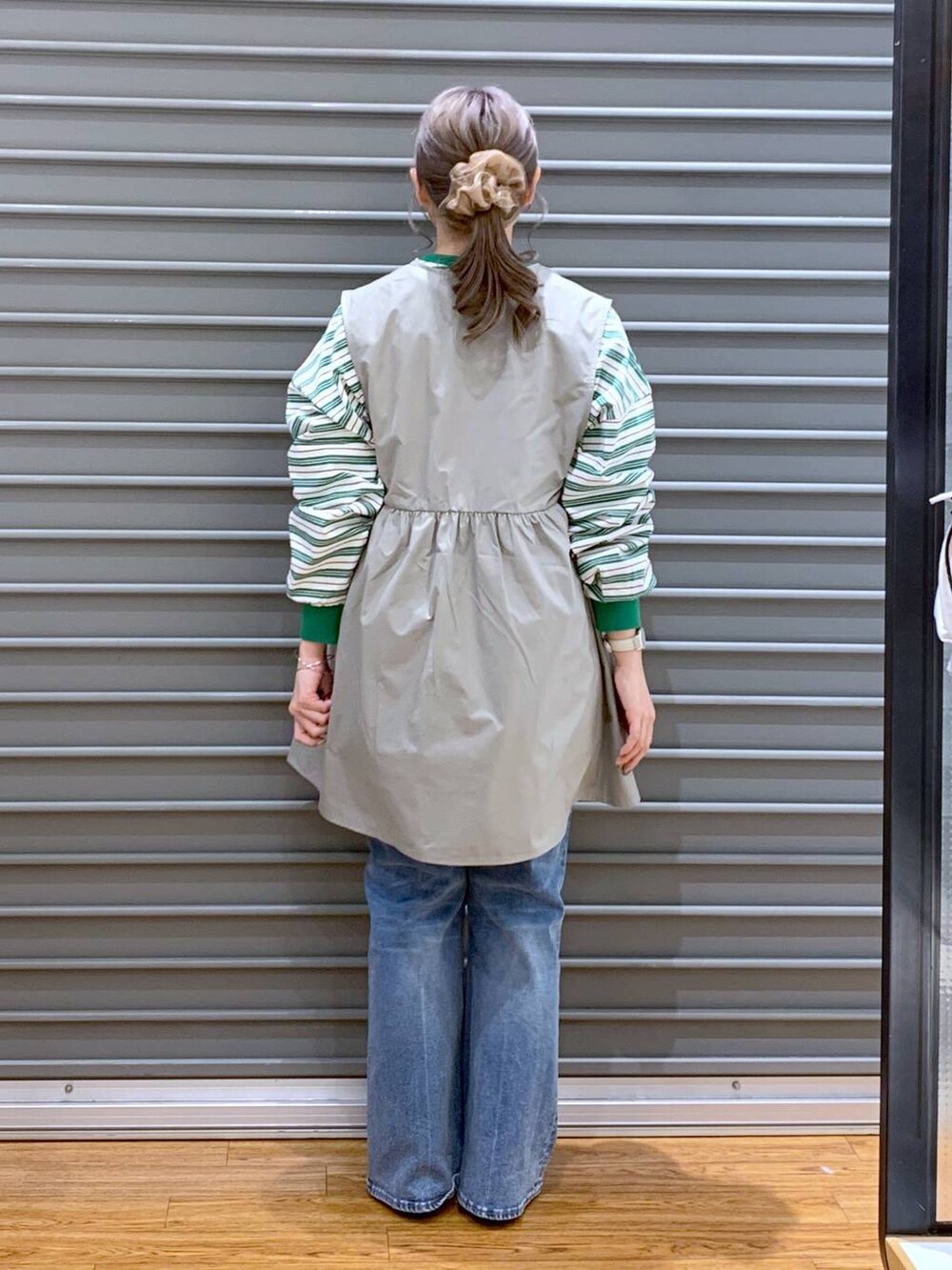 グリーン系のワンピース、ブルー系のデニムパンツ、ブラック系のパンプスを着用したレディースの春コーディネートの2枚目の写真