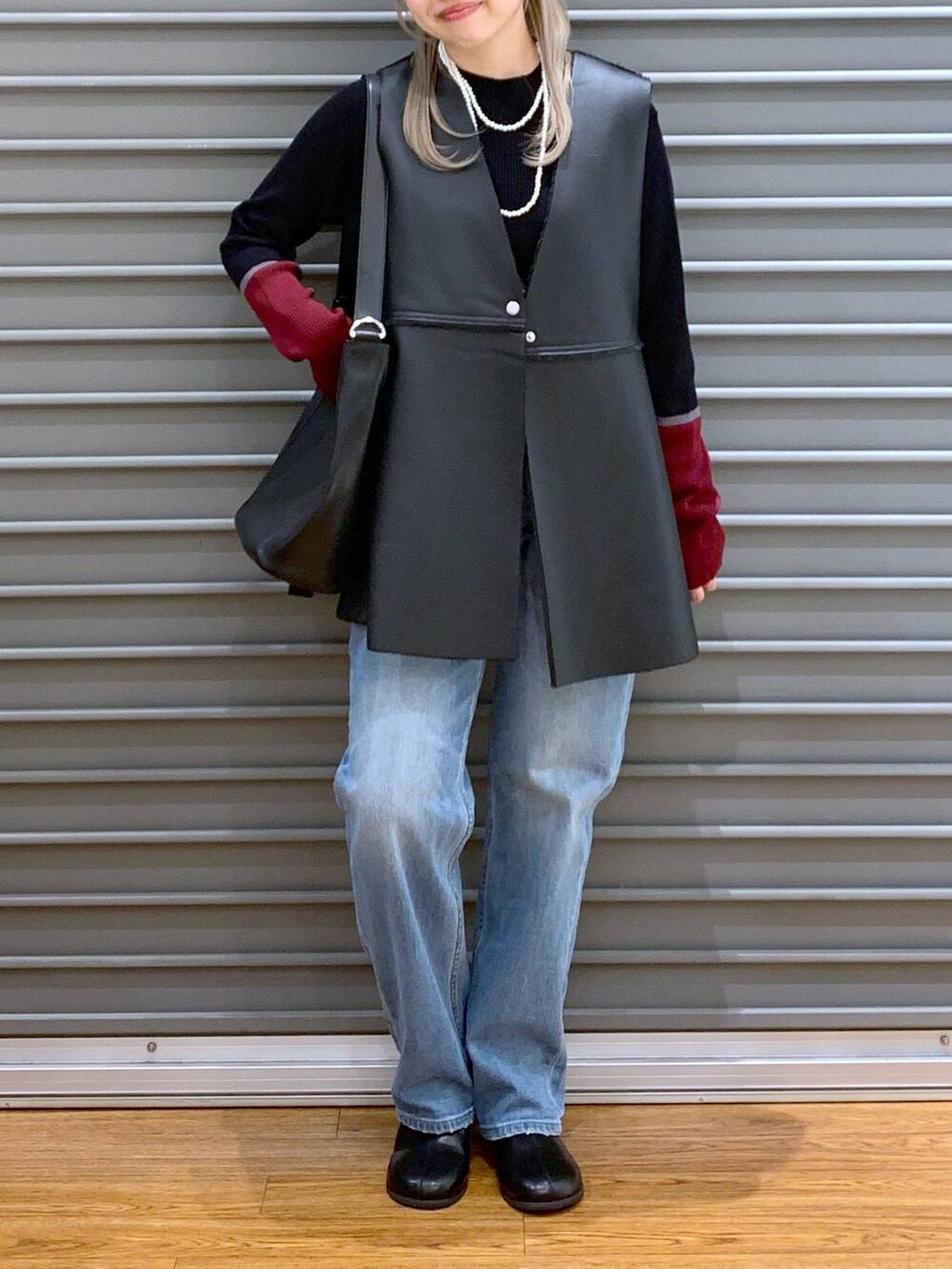 ブルー系のデニムパンツ、ブラック系のニット/セーター、ブラック系のショルダーバッグを着用したレディースの秋コーディネートの4枚目の写真