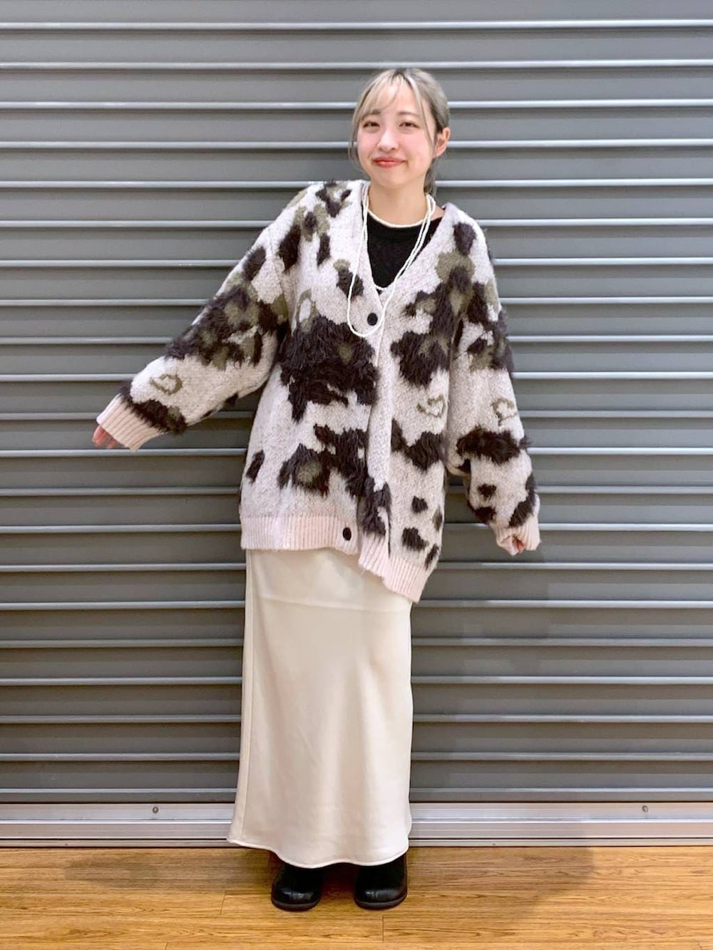 ホワイト系のスカート、ブラック系のショルダーバッグ、ブラック系のブーツを着用したレディースの冬コーディネートの5枚目の写真