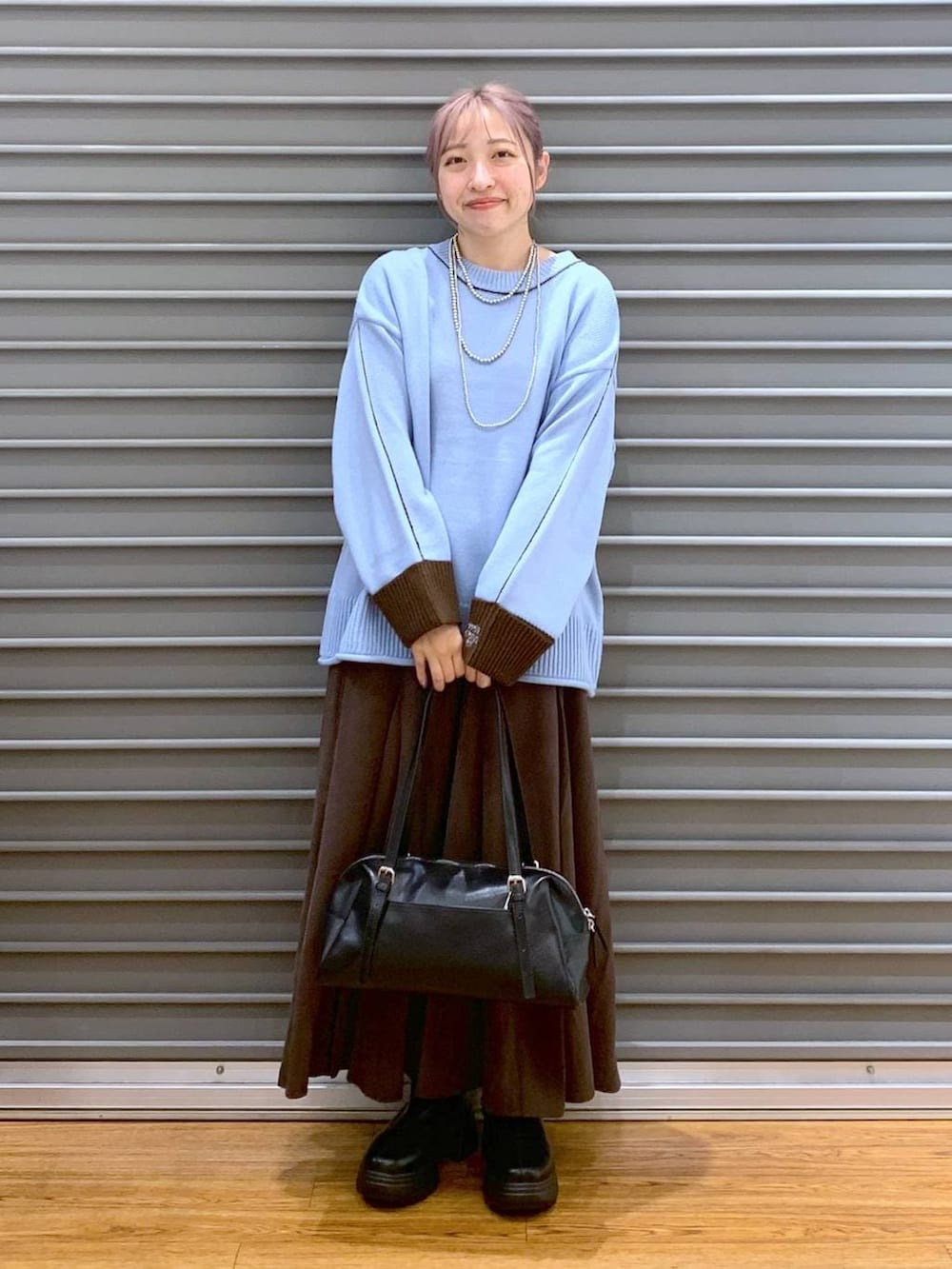 ブラック系のボストンバッグ、ブラック系のブーツ、ブラウン系のスカートを着用したレディースの冬コーディネートの4枚目の写真