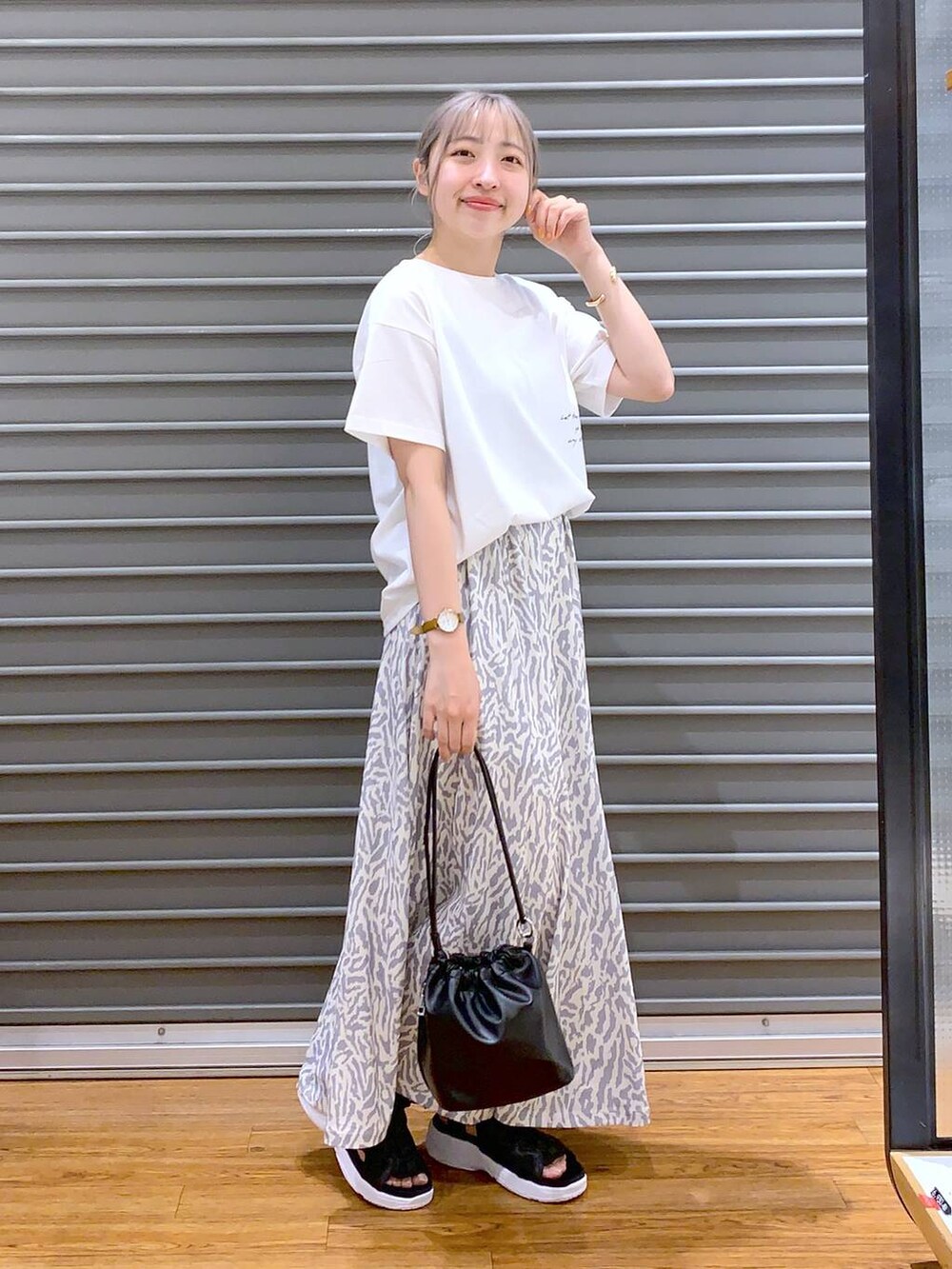 ブラック系のサンダル、ブラック系のショルダーバッグ、ホワイト系のスカートを着用したレディースの春コーディネートの5枚目の写真