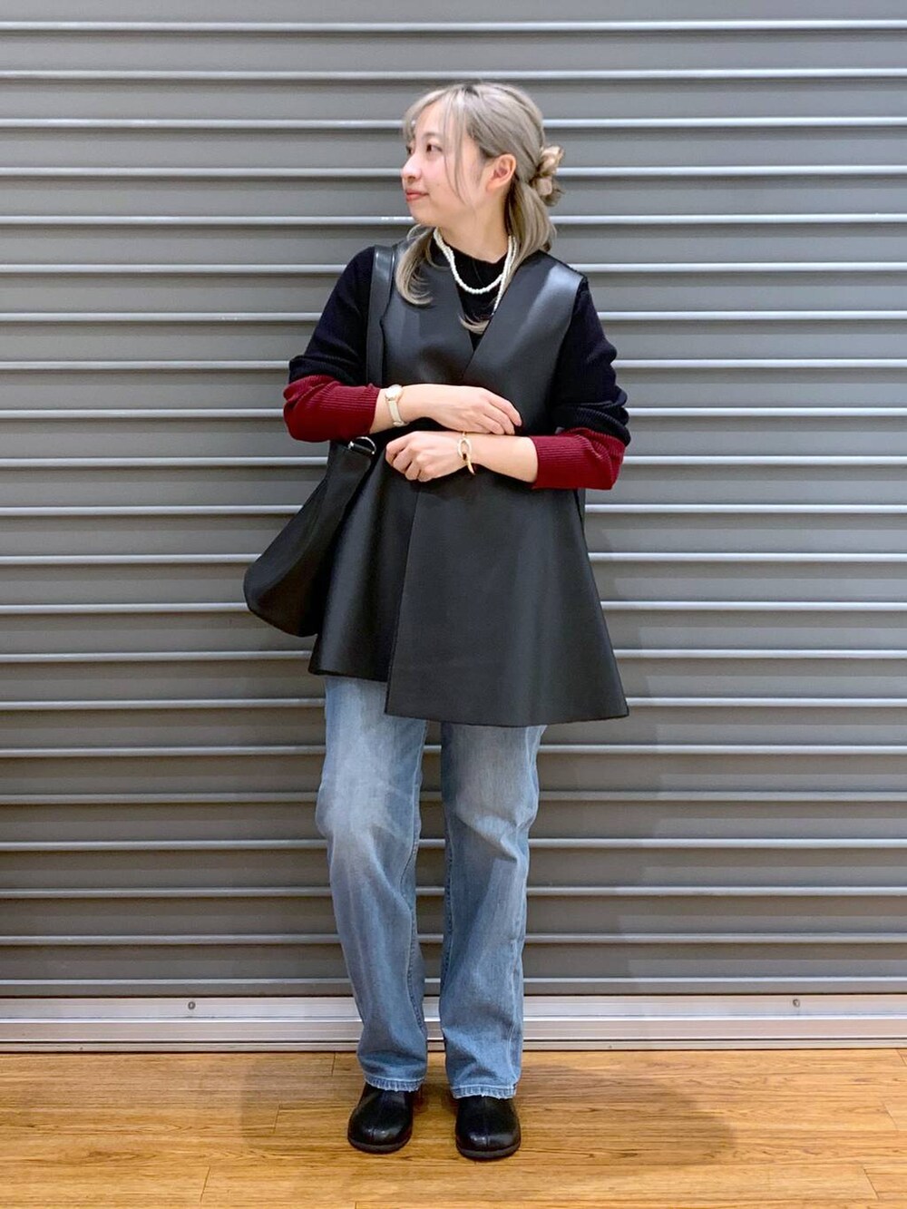 ブルー系のデニムパンツ、ブラック系のニット/セーター、ブラック系のショルダーバッグを着用したレディースの秋コーディネートの6枚目の写真