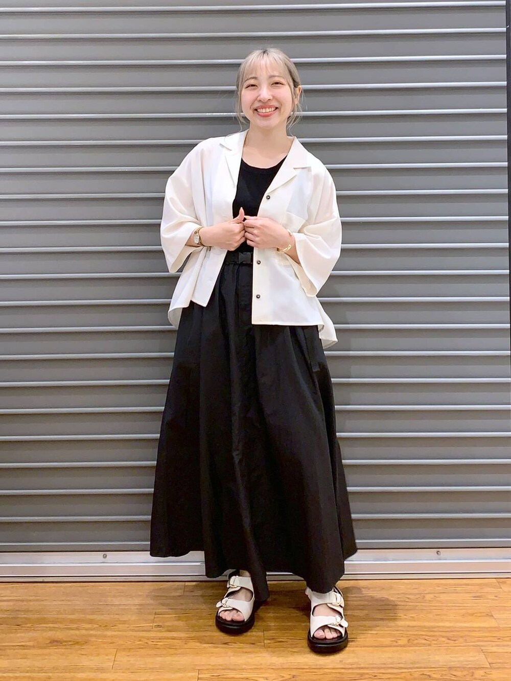 ブラック系のスカート、ブラック系のタンクトップ、ホワイト系のサンダルを着用したレディースの春コーディネートの4枚目の写真