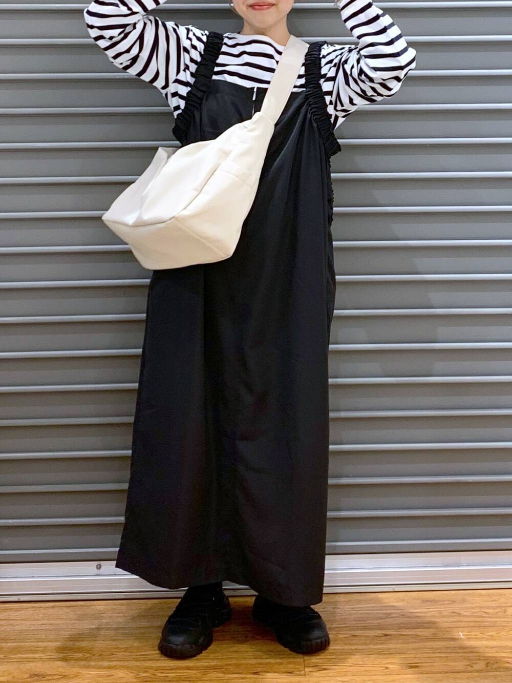 ブルー系のTシャツ/カットソー、ブラック系のスニーカー、ブラック系のジャンパースカートを着用したレディースの冬コーディネートの7枚目の写真