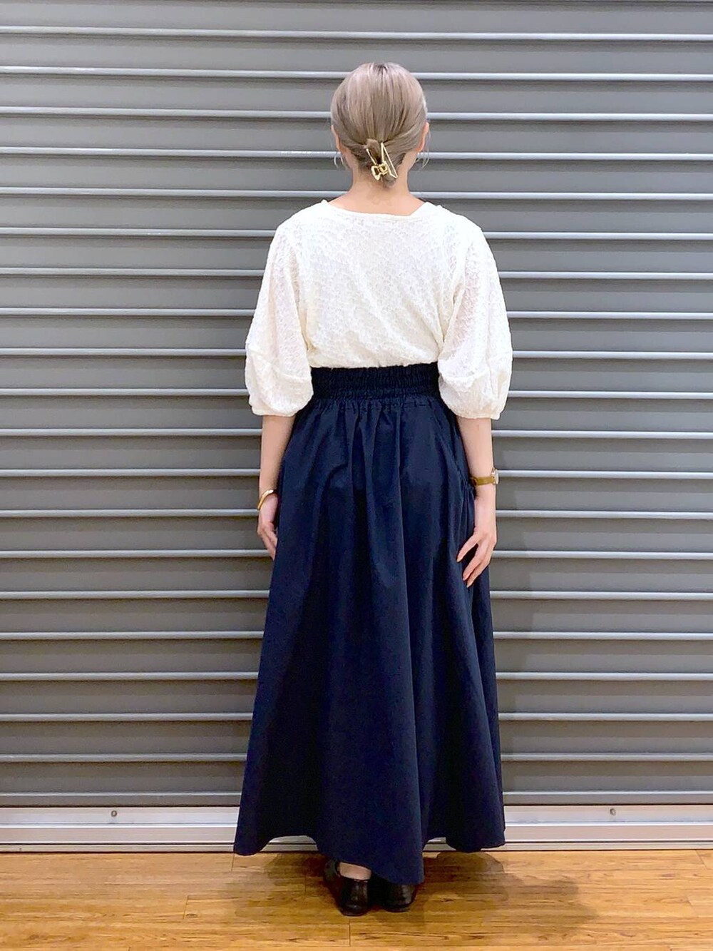 ホワイト系のショルダーバッグ、ブラック系のパンプス、ブルー系のスカートを着用したレディースの春コーディネートの2枚目の写真