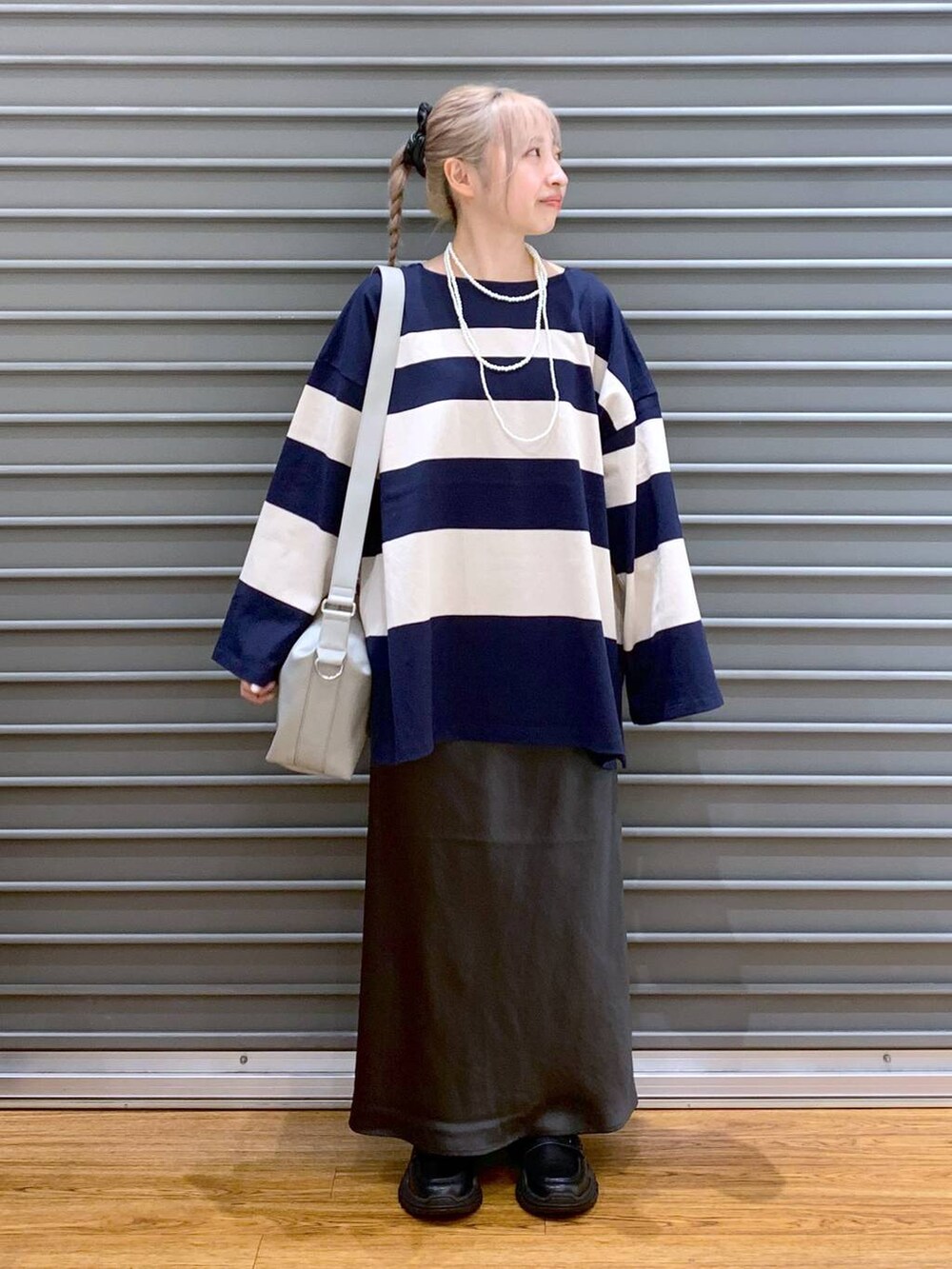 グレー系のスカート、グレー系のショルダーバッグ、ブラック系のスニーカーを着用したレディースの秋コーディネートの6枚目の写真