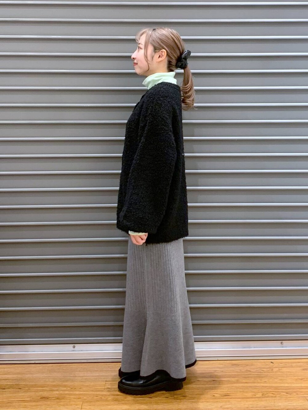 ブラック系のブーツ、ブラック系のワンピース、グリーン系のTシャツ/カットソーを着用したレディースの冬コーディネートの3枚目の写真