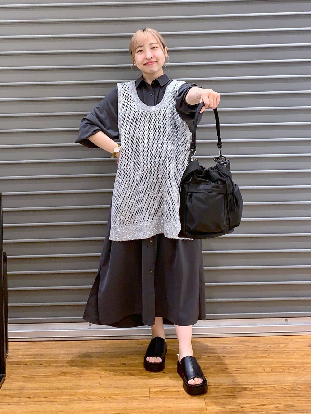 グレー系のベスト、グレー系のワンピース、ブラック系のショルダーバッグを着用したレディースの春コーディネートの4枚目の写真