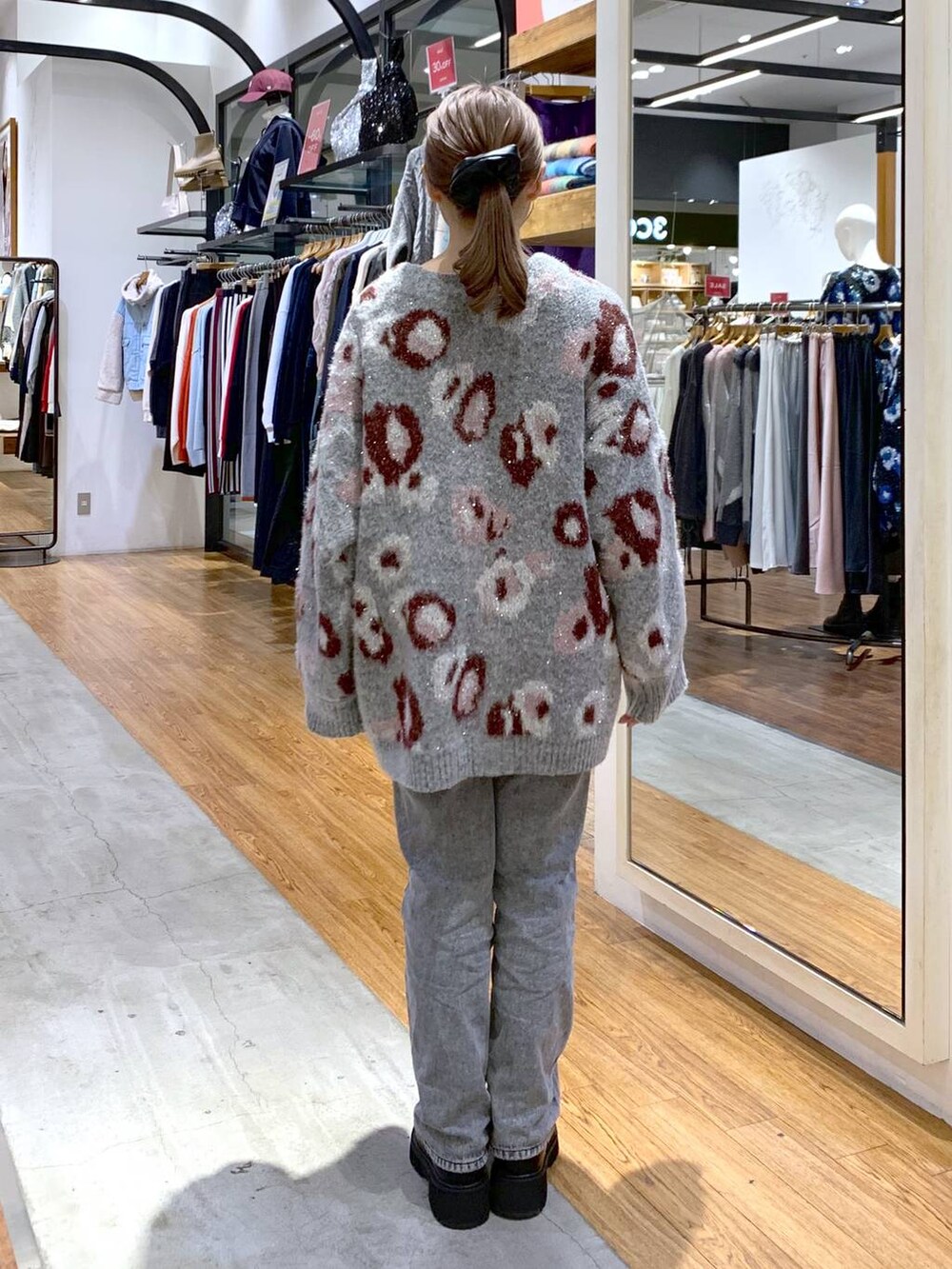 ブラック系のブーツ、グレー系のデニムパンツ、ホワイト系のショルダーバッグを着用したレディースの秋コーディネートの2枚目の写真