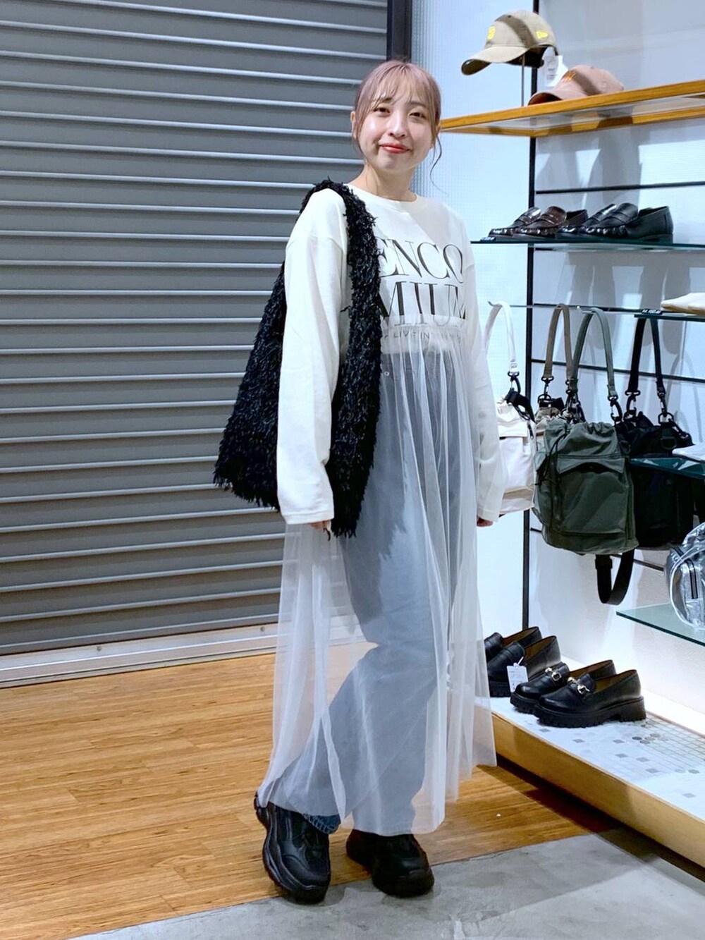 ブラック系のスニーカー、ブルー系のデニムパンツ、ブラック系のショルダーバッグを着用したレディースの秋コーディネートの4枚目の写真