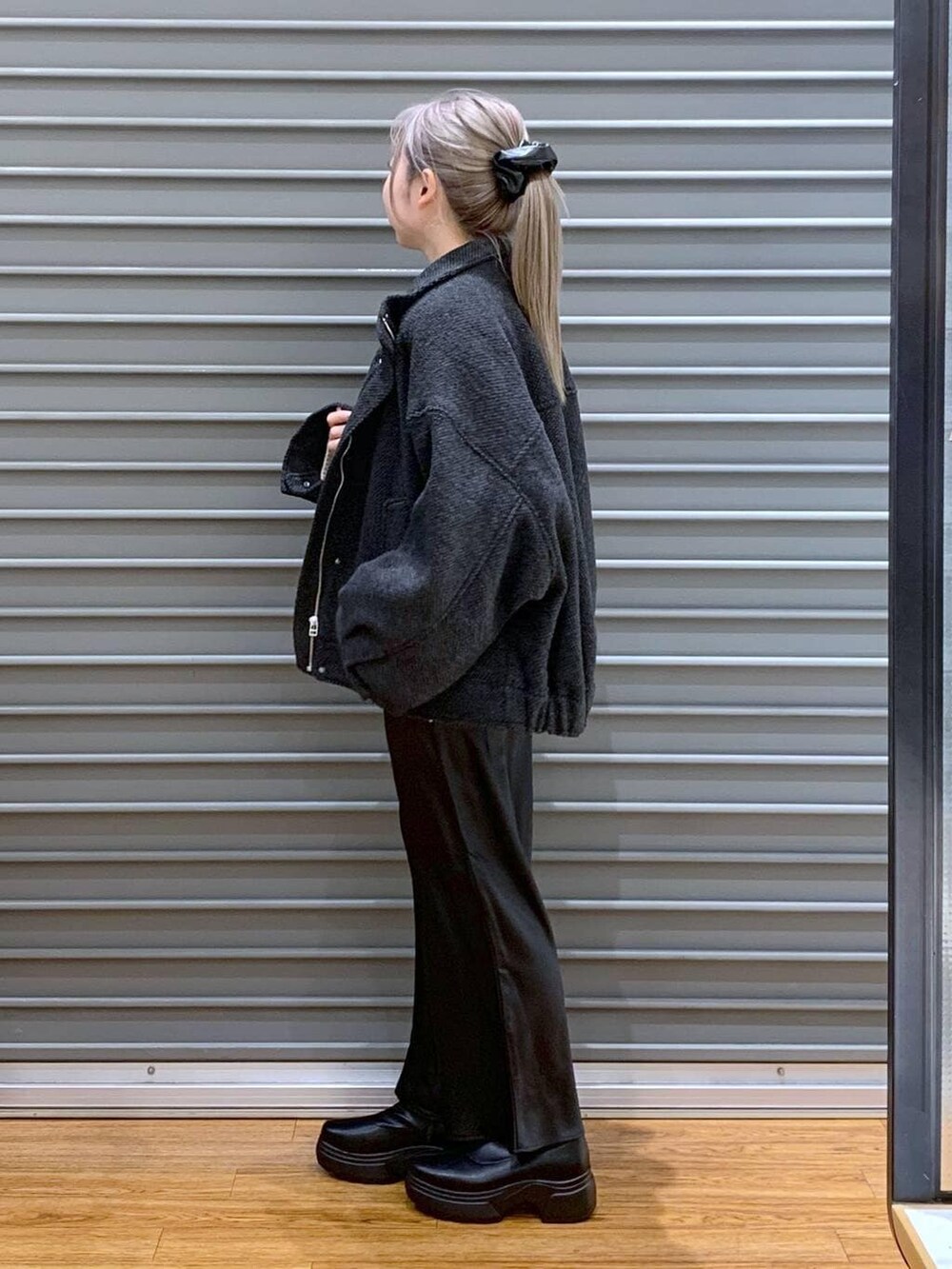 ブラック系のスカート、グリーン系のショルダーバッグ、ブラック系のブルゾンを着用したレディースの冬コーディネートの4枚目の写真