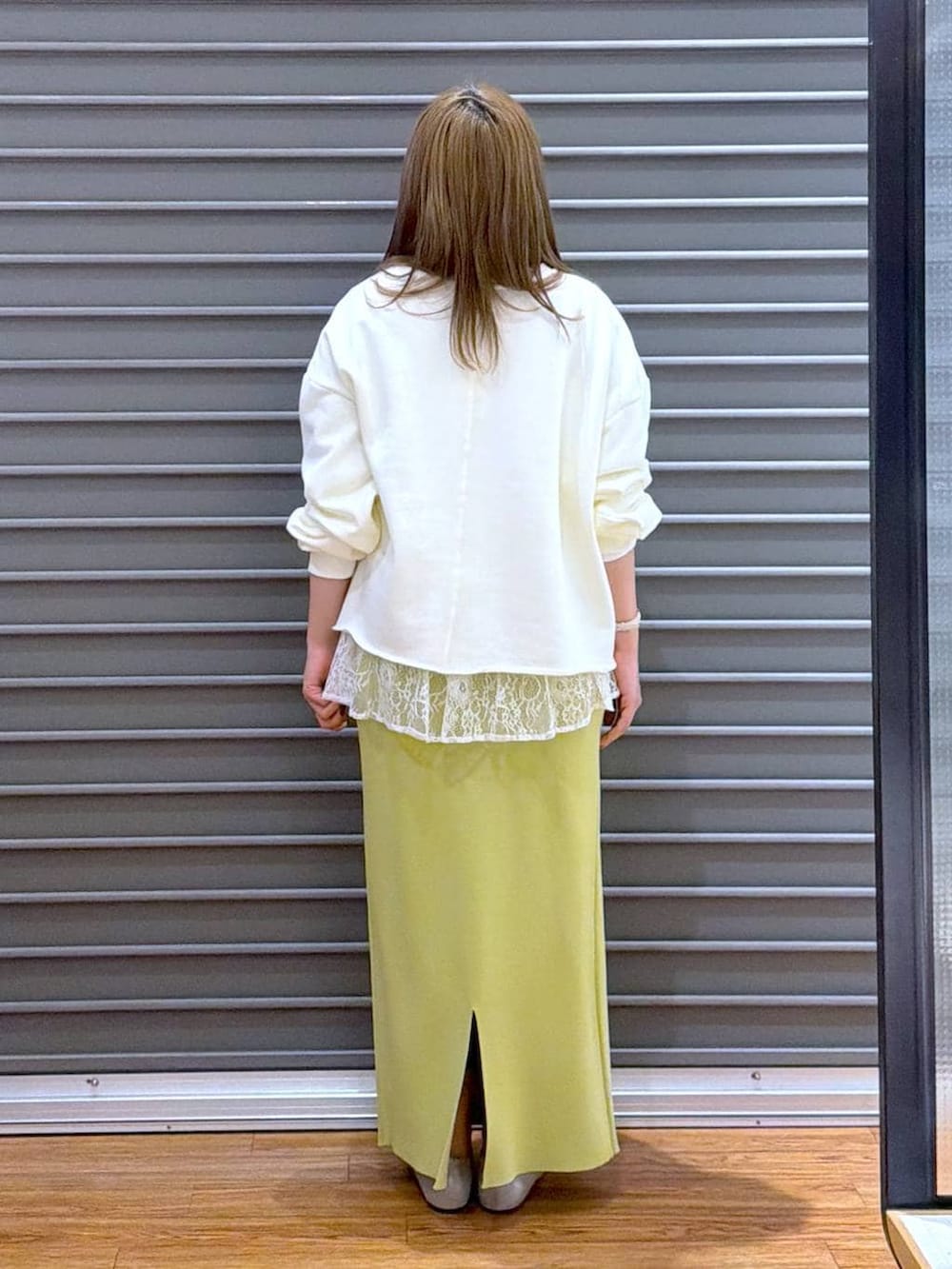 グリーン系のスカート、ホワイト系のTシャツ/カットソー、シルバー系のパンプスを着用したレディースの冬コーディネートの2枚目の写真