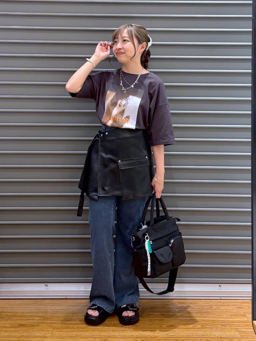 ブラック系のトートバッグ、ブラック系のサンダル、ブルー系のデニムパンツを着用したレディースの夏コーディネートの5枚目の写真