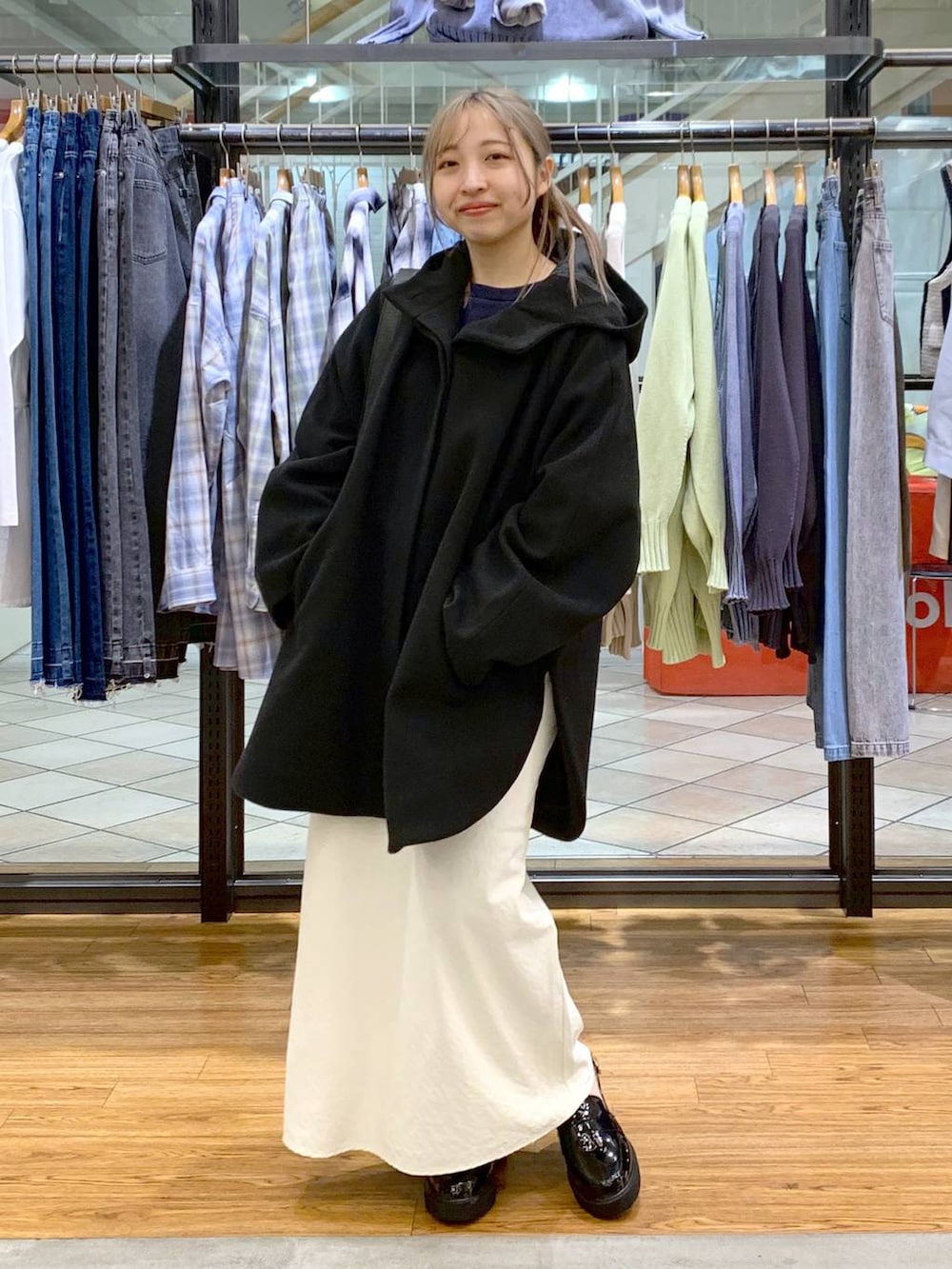 ブラック系のポンチョ、ホワイト系のスカート、ブラック系のショルダーバッグを着用したレディースの冬コーディネートの4枚目の写真