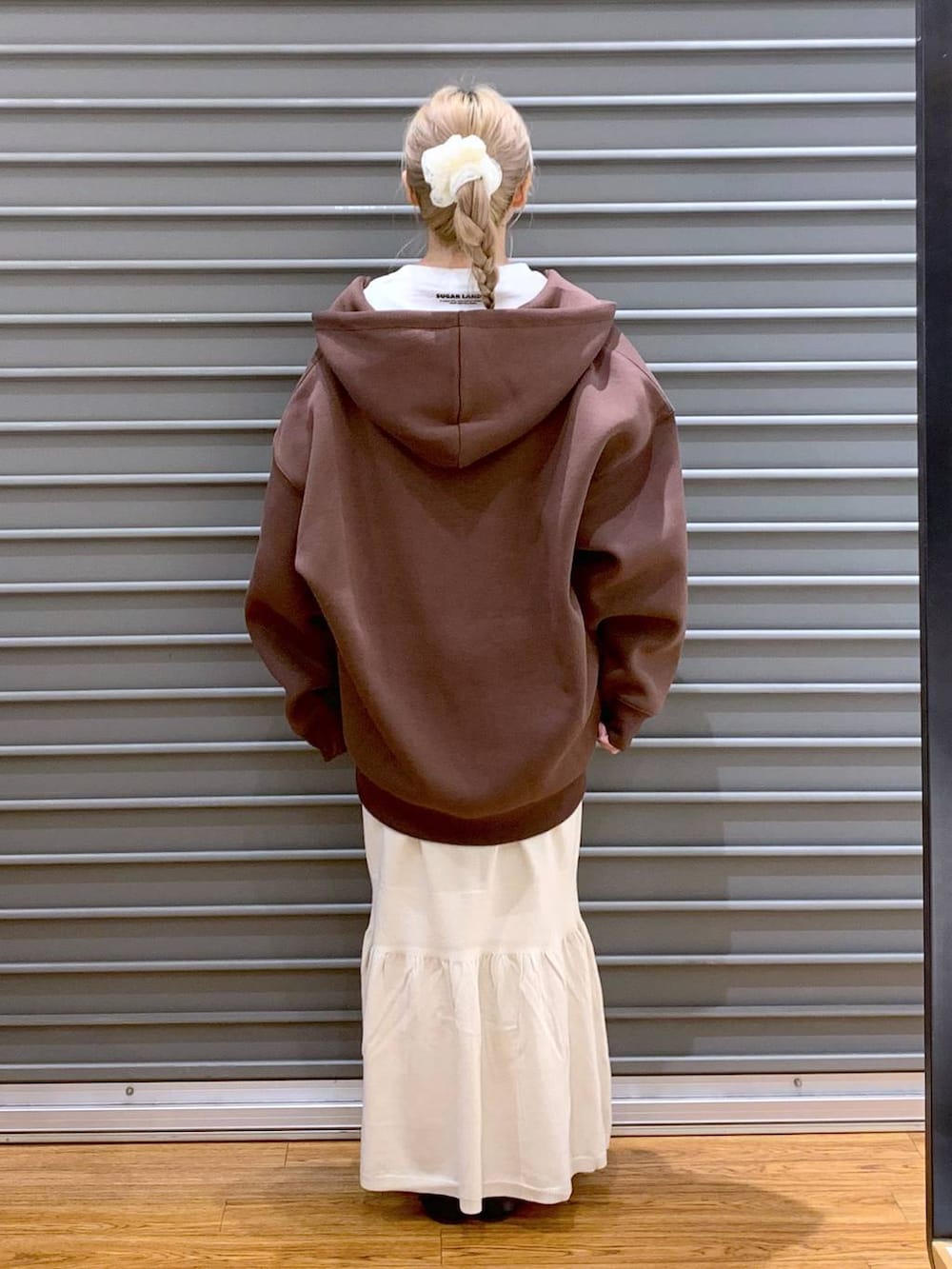 シルバー系のショルダーバッグ、ホワイト系のスカート、ブラウン系のパーカーを着用したレディースの秋コーディネートの2枚目の写真