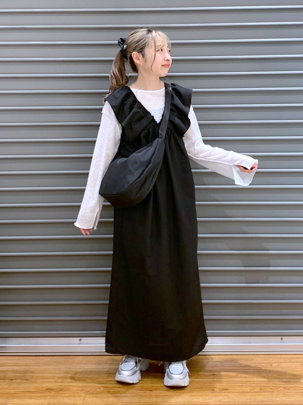 ブラック系のジャンパースカート、シルバー系のスニーカー、ホワイト系のTシャツ/カットソーを着用したレディースの春コーディネートの3枚目の写真