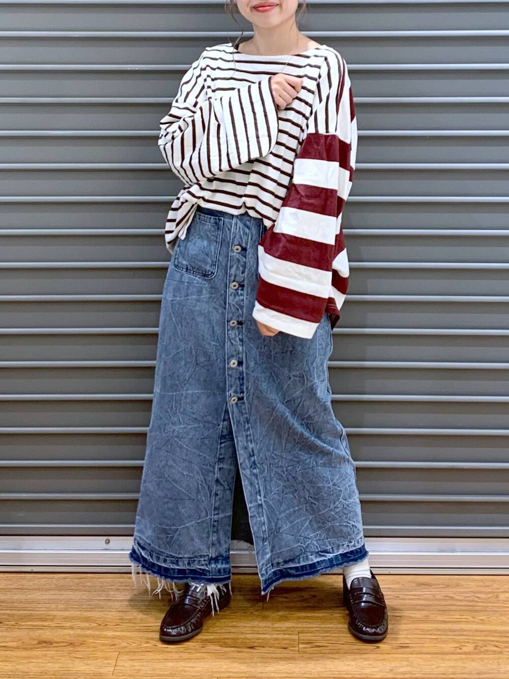 レッド系のTシャツ/カットソー、ブルー系のデニムスカート、ブラウン系のローファーを着用したレディースの秋コーディネートの3枚目の写真