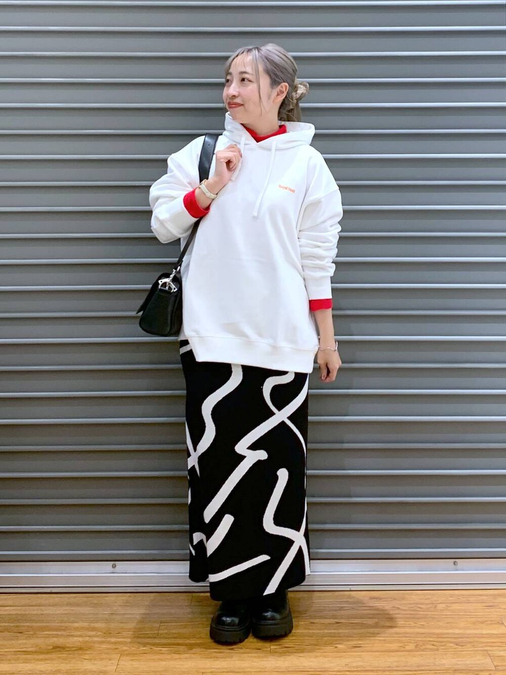 ブラック系のスカート、ブラック系のショルダーバッグ、ブラック系のブーツを着用したレディースの冬コーディネートの4枚目の写真