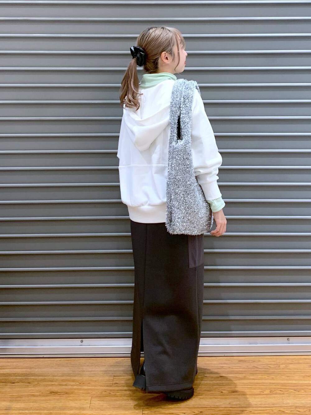 ブラック系のブーツ、シルバー系のショルダーバッグ、グレー系のスカートを着用したレディースの冬コーディネートの5枚目の写真