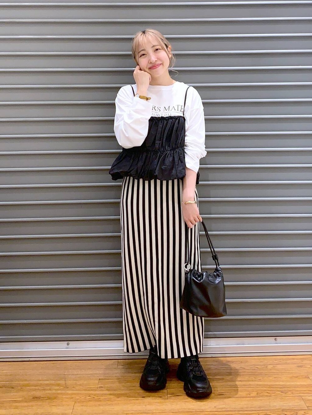 ブラック系のショルダーバッグ、ブラック系のスニーカー、ホワイト系のスカートを着用したレディースの春コーディネートの5枚目の写真