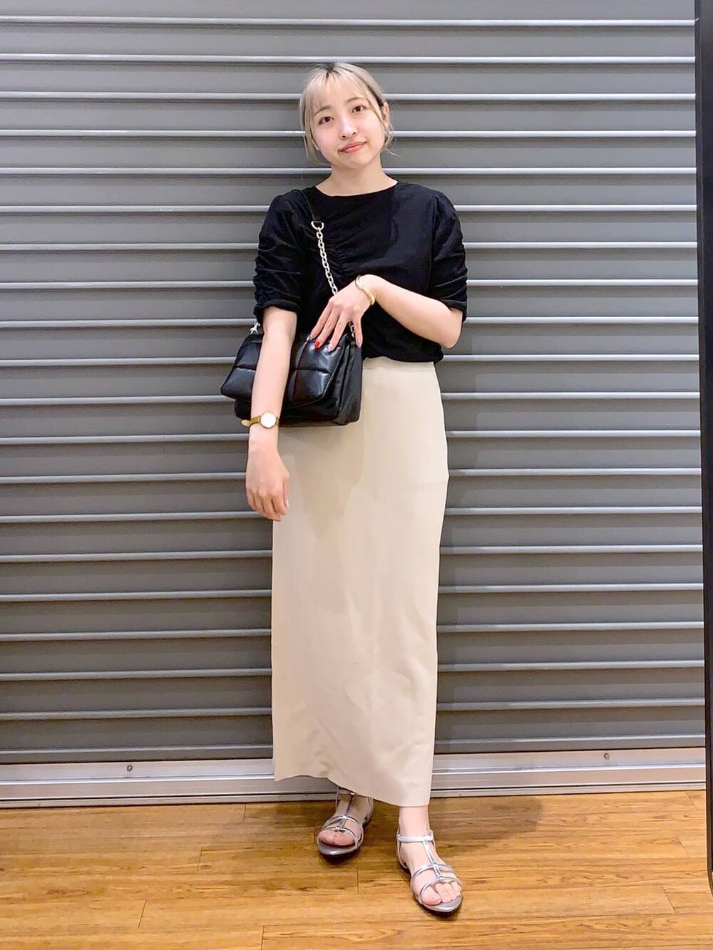 ブラック系のショルダーバッグ、ベージュ系のスカート、シルバー系のサンダルを着用したレディースの春コーディネートの6枚目の写真