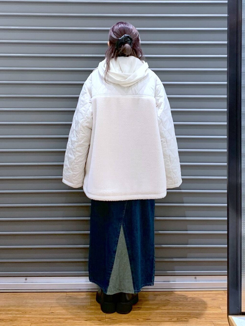 ホワイト系のショルダーバッグ、ブルー系のジャンパースカート、ブラック系のブーツを着用したレディースの冬コーディネートの2枚目の写真