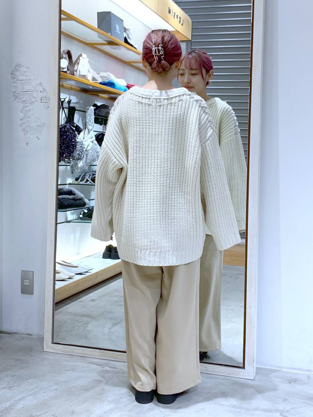 ブラック系のブーツ、ホワイト系のニット/セーター、ブラック系のハンドバッグを着用したレディースの秋コーディネートの2枚目の写真